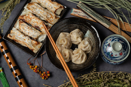 Material of traditional chinese fried dumplings(also called gyoza,pot sticker) on table with black background and decorate with chinese style fans and tea cup.の写真素材