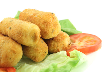 Plate of potato croquettes over lettuce and tomatoes. Close-up view.