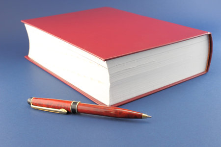 Red book with an elegant pen in front.