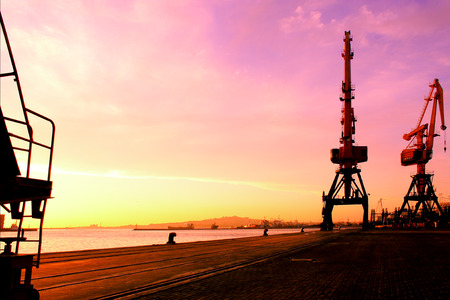 Silhouette of two heavy cranes at sunset harbor. Conceptual image about business and exports.のeditorial素材