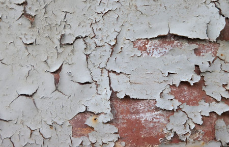 Peeling paint on a primed metal surface.