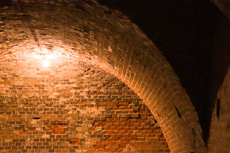 Wall and vault of an old military fort, illuminated by a lamp.の写真素材