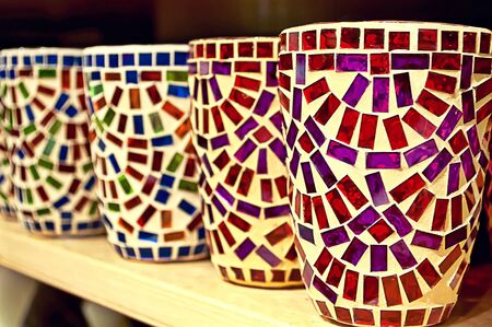 Clay cups with colourful mosaic on a shelfの写真素材