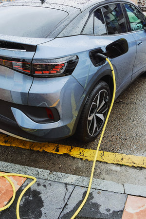 Electric car on a rainy day connected to charging cableの写真素材