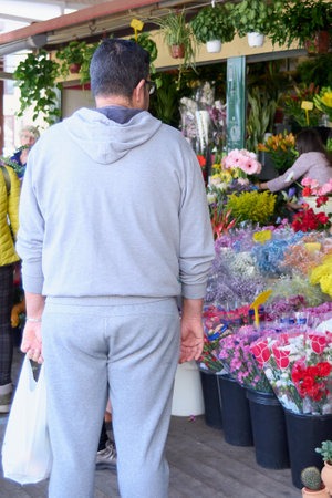 Man queuing to buy flowers at a street stall on a sunny day. In the concept of home decoration.のeditorial素材