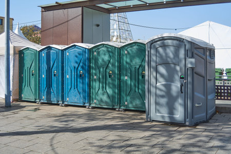 Six plastic toilet cabins of different colors.