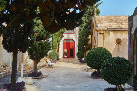 Pathway with ornamental trees leading to the red exit door of the cemetery.の写真素材