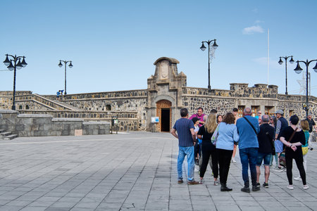 Puerto de la Cruz, Tenerife, Spain - July 01, 2023: Group of tourists in front of the wall of Castillo de Sant Felipe at Plaza de Europa in Puerto de la Cruz, Tenerife, Canary Islands.のeditorial素材