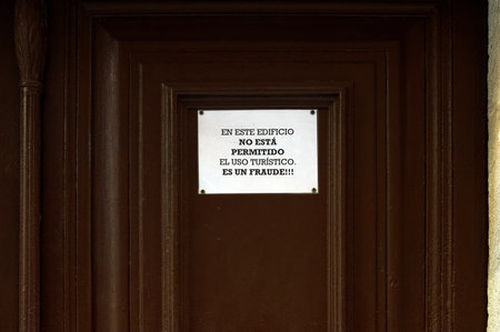 Image of a warning sign stuck on a brown door indicating the prohibition of tourist use of the building, calling it a fraud. Translation: Tourist use is not allowed in this building, it is a fraudの写真素材