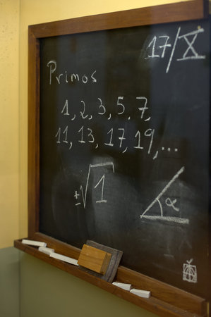 Classroom blackboard showing a list of prime numbers and geometric drawings, ideal for educational...