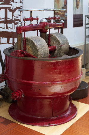Close-up of an antique machine used in the chocolate making process, showing worn gears and...
