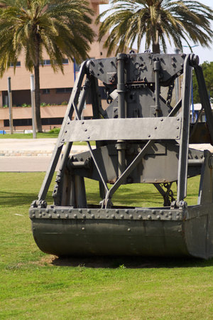 The structure of a historic crane contrasts with nature in a Tarragona park, reflecting the fusion...