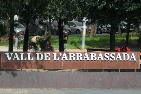 Tarragona, Spain - April 6, 2024: Image captures a sunny day in the Vall de L'Arrabassada park, showing people enjoying and relaxing outdoors, with green trees and parked cars in the background.のeditorial素材