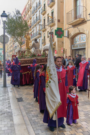 Tarragona, Spain - April 23, 2024: Traditional procession with purple-robed penitents on a...