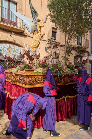 Tarragona, Spain - April 26, 2024: Authentic capture of an Easter procession on a historic street in Tarragona, showcasing participants dressed in traditional robes carrying a floatのeditorial素材