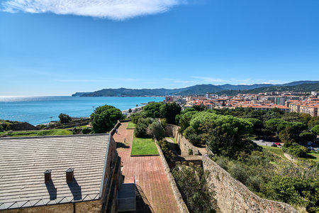 The Priamar Fortress in Savona, Italy, with its ancient stone walls and a panoramic view of the harbor and city, under a bright blue sky. Concept: Historical and travel themes.の写真素材