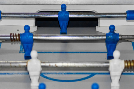 The image highlights foosball players on a gray playing field with blue lines. The vibrant colors...