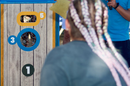 A close-up of a cornhole game scene highlighting a determined female player ready to score on a bright board in a fun competition.の写真素材