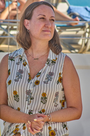 A candid shot of a relaxed woman in casual attire, adorned with a necklace and smiling naturally.