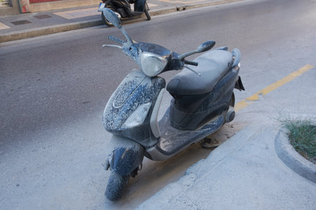 Dusty motorcycle parked on a city street with visible dirt and grime, reflecting the effects of urban pollution and neglect over time.の写真素材