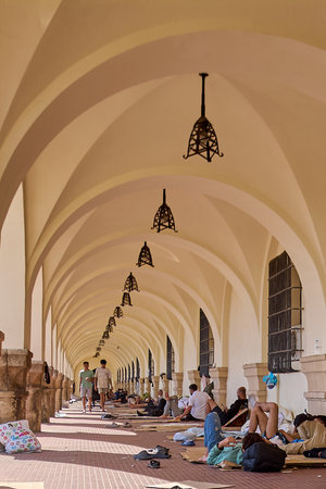 Rhodes.Greece - June 05, 2025: Arched hallway of a historic building, identified as the Old Governors Palace, with people and belongings, showing a scene of rest and shelter.の写真素材