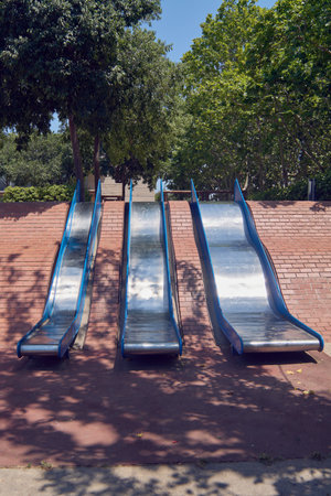 A row of empty slides in a park, evoking a sense of nostalgia, childhood memories, or the simple joy of outdoor play.の写真素材