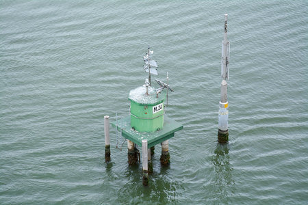 A marine monitoring station with solar panels and antennas, fixed on a platform in the water, is...