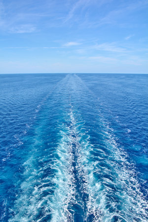 The trail of a cruise ship on the sea surface on a clear day. An image that evokes concepts of travel, vacation, and maritime exploration.の写真素材
