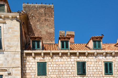 A clear blue sky highlights the red tile roofs and green shutters of the historic architecture in Stari Grad.の写真素材