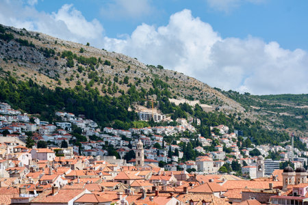 Dense orange terracotta rooftops of Dubrovnik's old town, a UNESCO world heritage site, with the hillside of Mount Srd in the background on a summer day.の写真素材