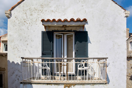 Mediterranean architecture on a sunny day. Two chairs on a small balcony invite relaxation. Summer vacation lifestyle on the Adriatic coast in Europe.の写真素材