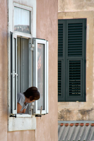 Vertical view of authentic life in Dubrovnik. A woman looks down from her apartment in the Old Town....