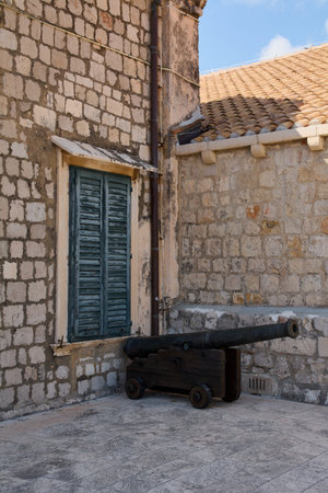 An old cannon on a wooden carriage on the city walls of Dubrovnik, Croatia. Historic stone wall with green wooden shutters.の写真素材