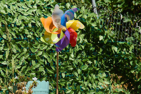 Colorful multi-colored pinwheel toy catching the light in a lush garden, symbolizing childhood joy,...