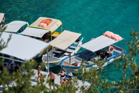 Corfu. Greece - January 22, 2026: High-angle shot of excursion boats and tourists on a jetty, surrounded by the stunning emerald sea of the Ionian Islands in Greece.のeditorial素材