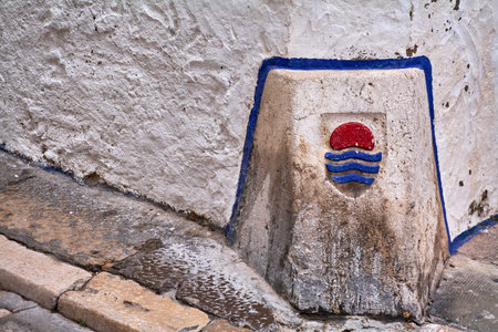 Sitges. spain - february 18, 2026: Close up of maritime emblem embedded in historic alley wall in sitges center, mediterranean identity and urban detailのeditorial素材