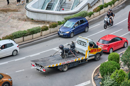 Kotor. Montenegro - March 24, 2026: A tow truck carries a scooter through city traffic. The flatbed...