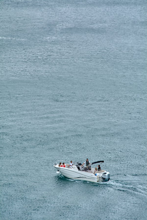 Kotor. Montenegro - March 24, 2026: A white speedboat with passengers cruises across the vast blue...