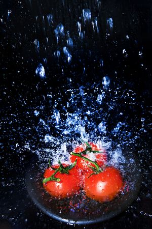 Fresh tomatoes under running tap with water dropsの写真素材