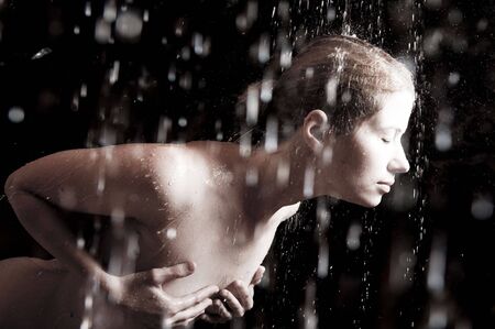 The young sexual woman in splashes of water. Flying drops. Water studio photo.の写真素材