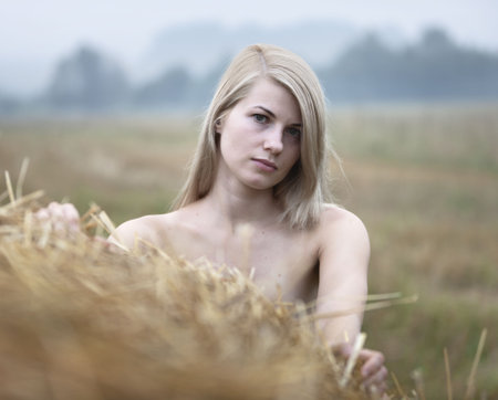 Young sexy woman on a summer day among the straw.の写真素材