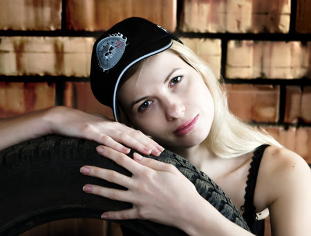 Sexy blonde with a car tire on the background of a brick wall.の写真素材