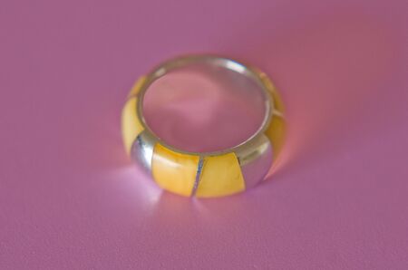 close up of a silver and amber ring on a pink backgroundの写真素材