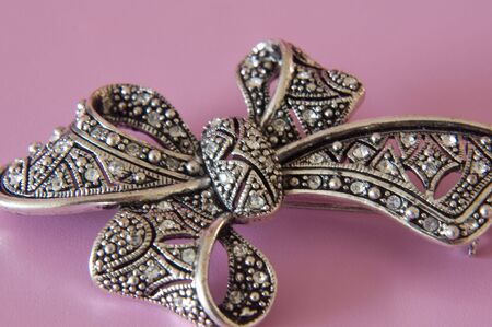 close up of a vintage bow brooch on a pink backgroundの写真素材