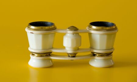 a pair of old ivory binoculars isolated on a yellow backgroundの写真素材