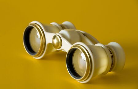 a pair of old ivory binoculars isolated on a yellow backgroundの写真素材