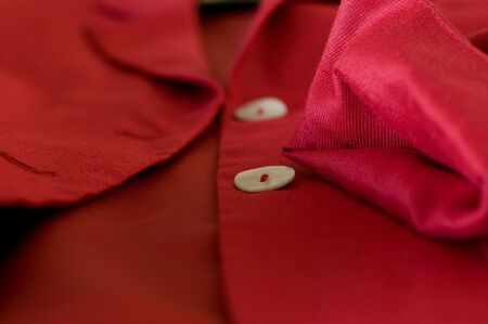 detail of a red female business suit with a folded sleeve and two pearl buttonsの写真素材