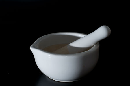 white ceramic mortar with pestle isolated on blackの写真素材
