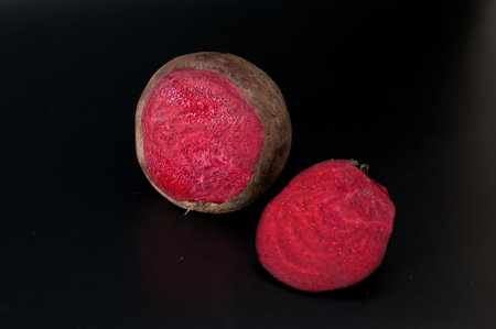 raw beetroot  cut into two isolated on black