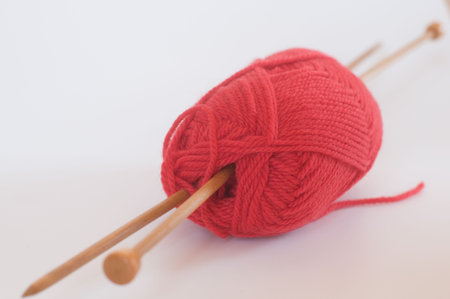 close up of red knitting yarn and two knitting needles